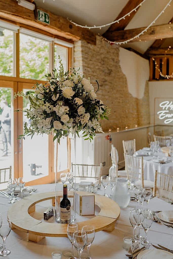 Tall floral display on wedding breakfast table in white and green blooms