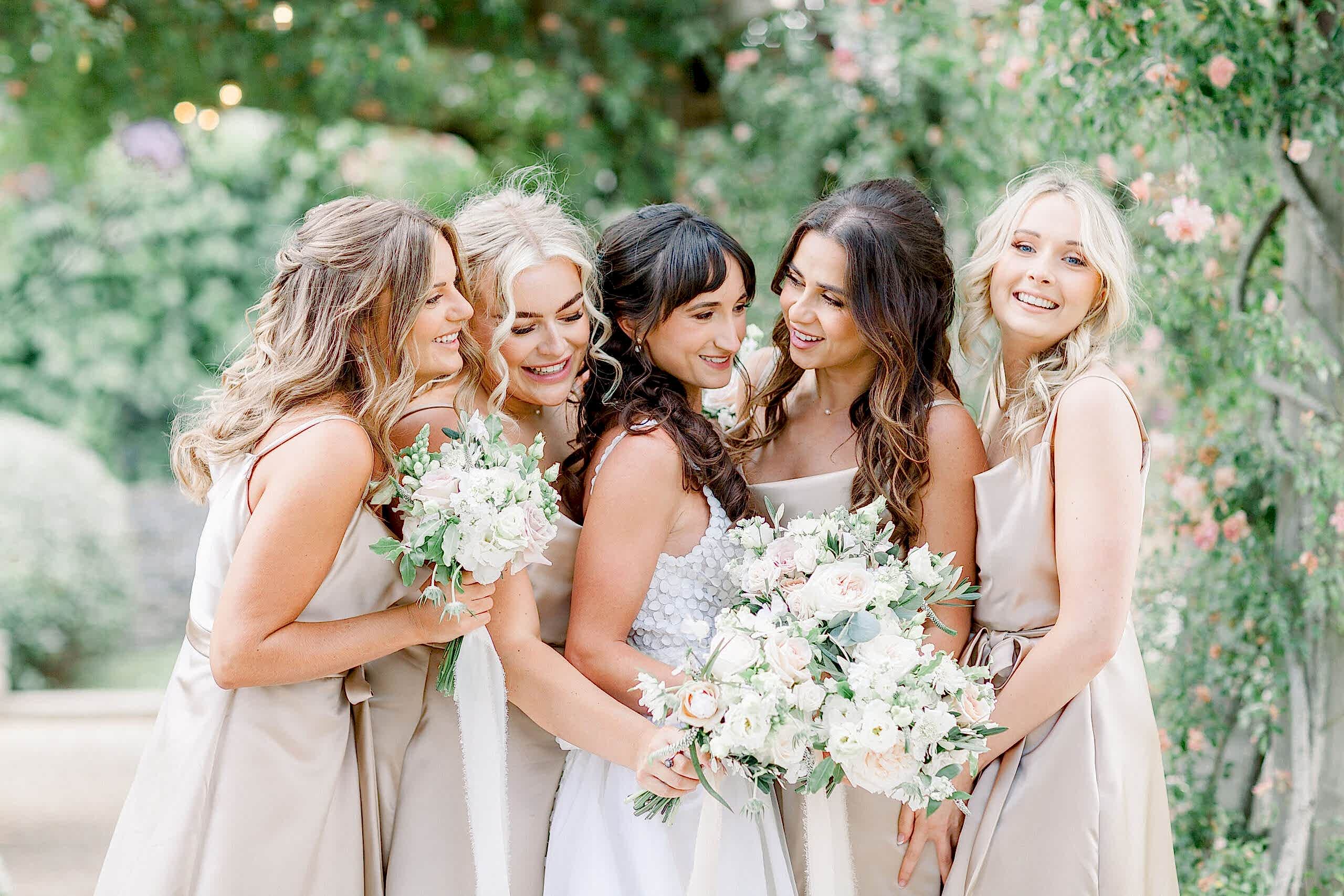 Amabel & Ollie - Euridge Manor - Jo Bradbury Photography Bride and Bridesmaids gathered together with flowers under foliage