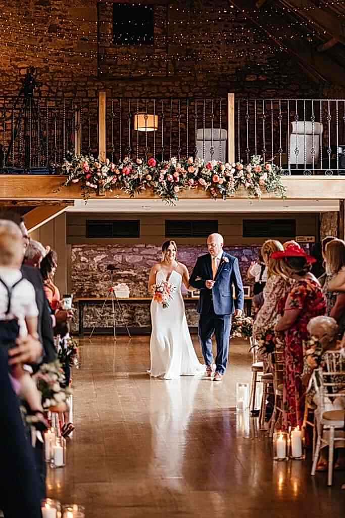 Bride and Brides Father walking down the aisle holding flowers