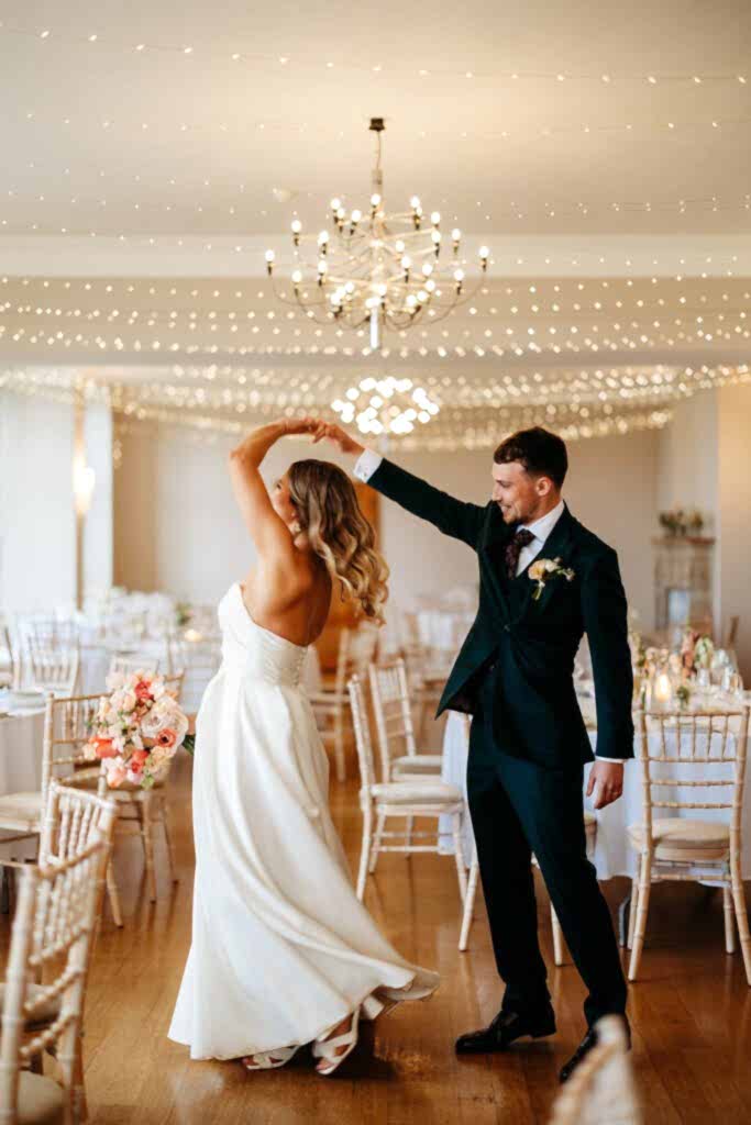 Bride and groom dancing at their wedding reception carrying florals